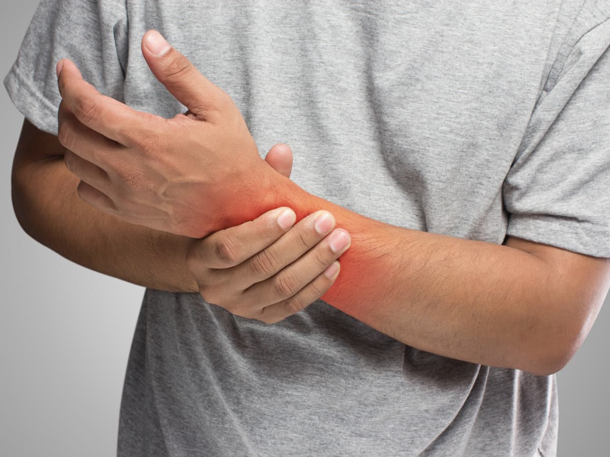 Close-up of a person holding their wrist with a red glow indicating pain, highlighting the risk of bone fractures associated with osteoporosis.